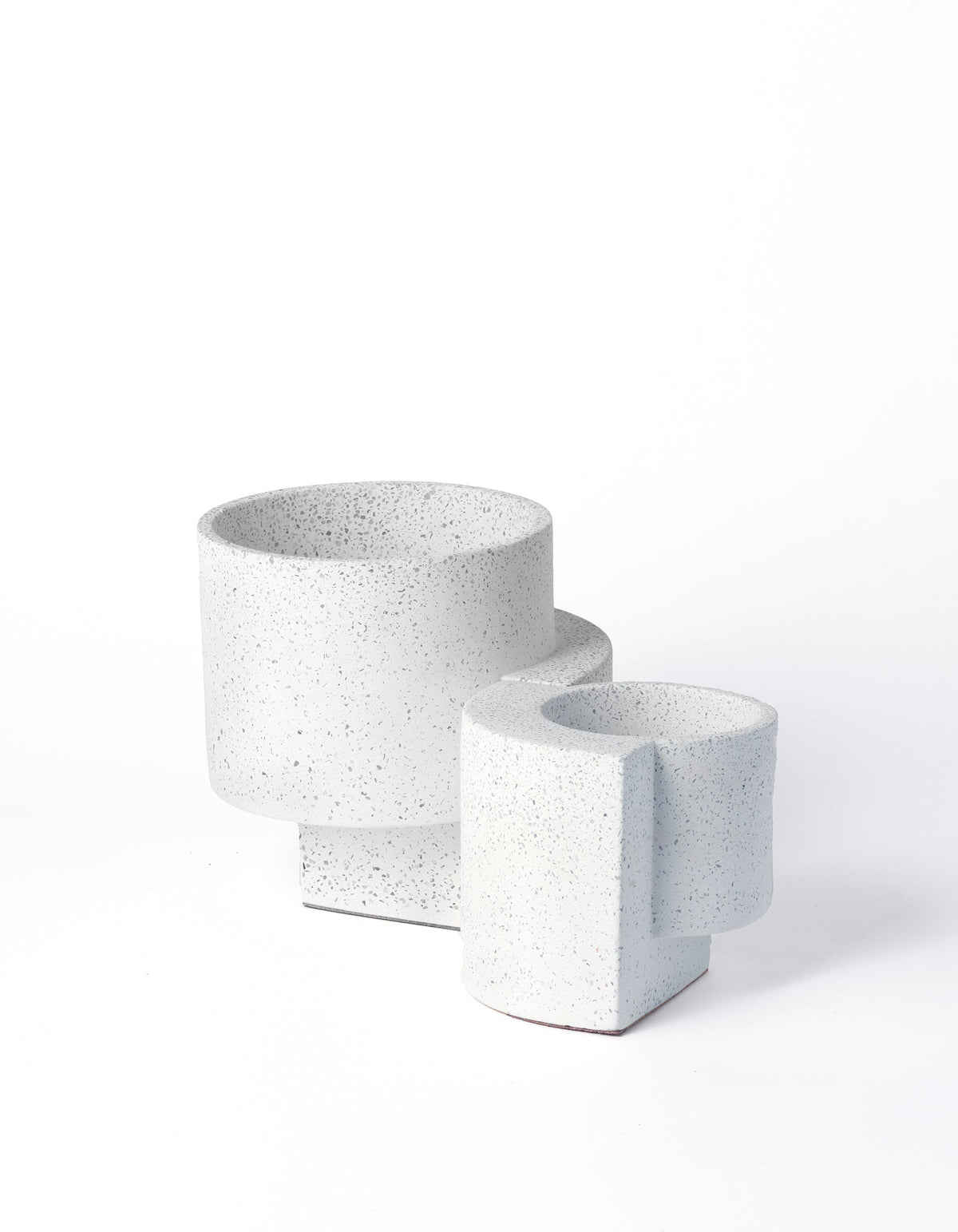 White Tortuga Forma Platform Planter Set viewed at an angle on white, showing two sizes with fine grey speckles, round planting cavities and geometric supports beneath the cylindrical pots.
