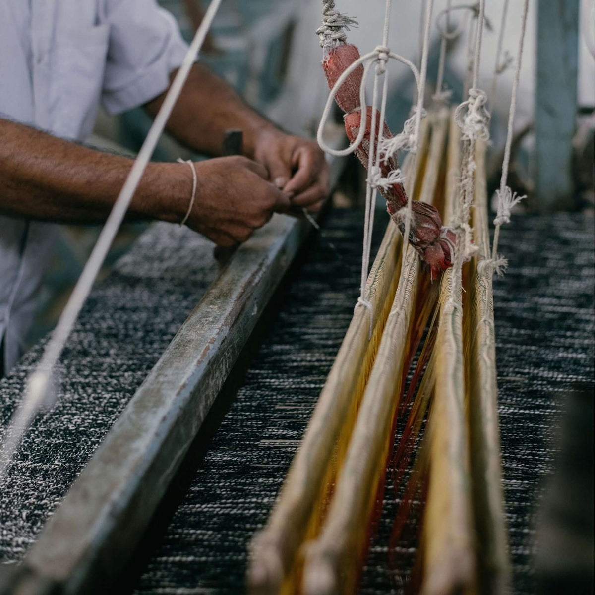 Close view of an artisan working the loom threads used to create the Silica Chalk handwoven throw