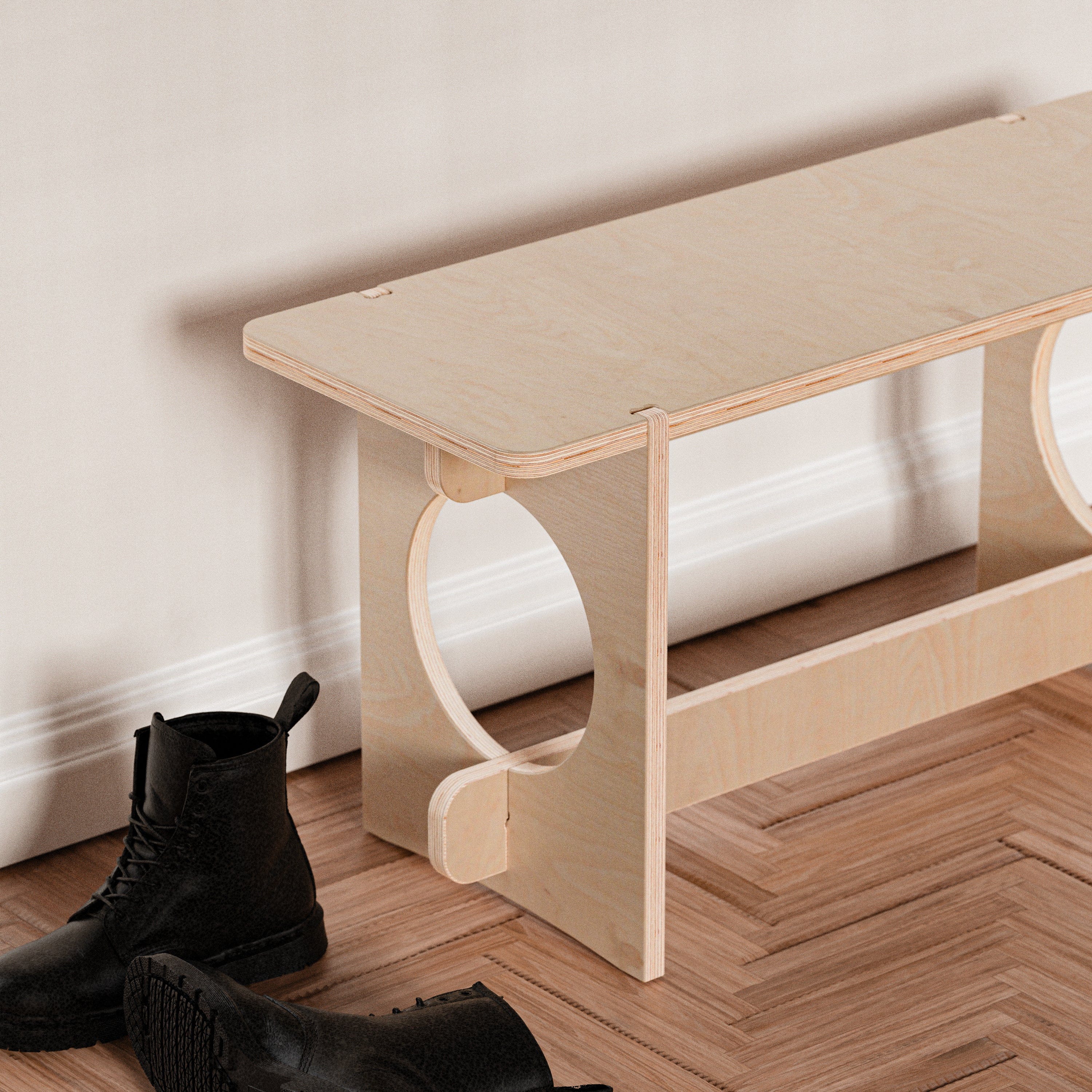 YOYO natural wood bench against a white wall with black boots placed beside and beneath it