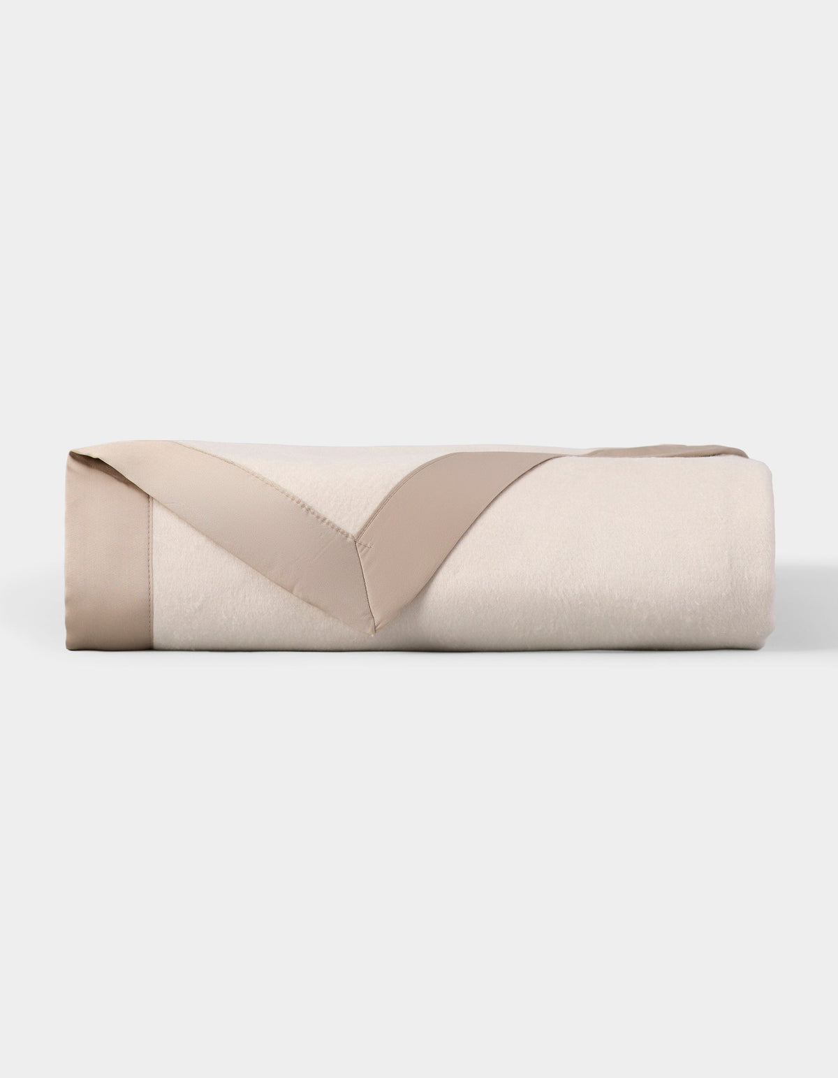 Ivory blanket folded into a rectangular stack, with its taupe satin border turned back in a V shape across the front.