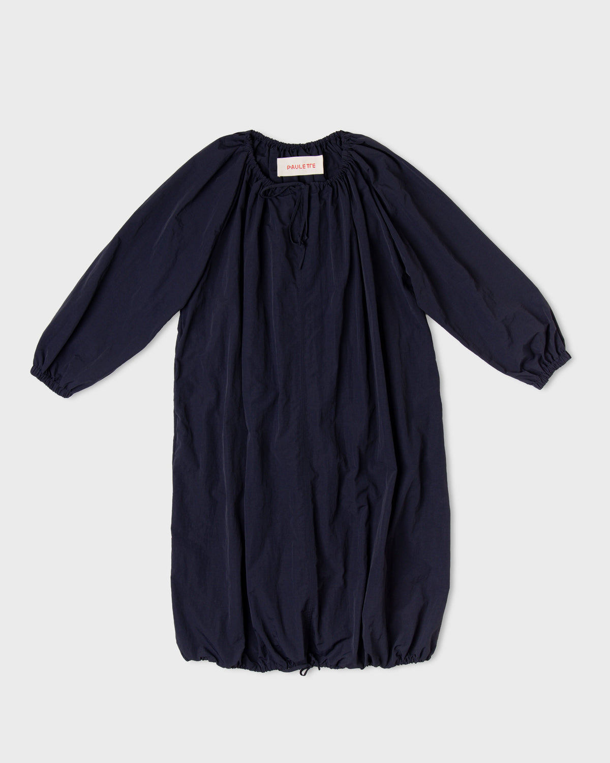 Dark navy Paulette Georgia Dress displayed against a light background, showing gathers around the neckline, voluminous long sleeves, narrow cuffs, and a rounded skirt gathered at the hem.