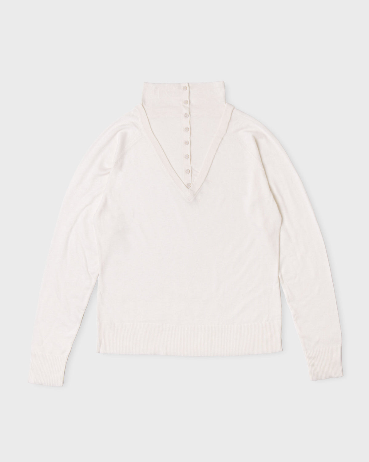 Ivory Paulette Montagne Top displayed against a light background, showing a tall collar, small buttons along a tapered front placket, softly gathered shoulders, long sleeves, and a straight hem.