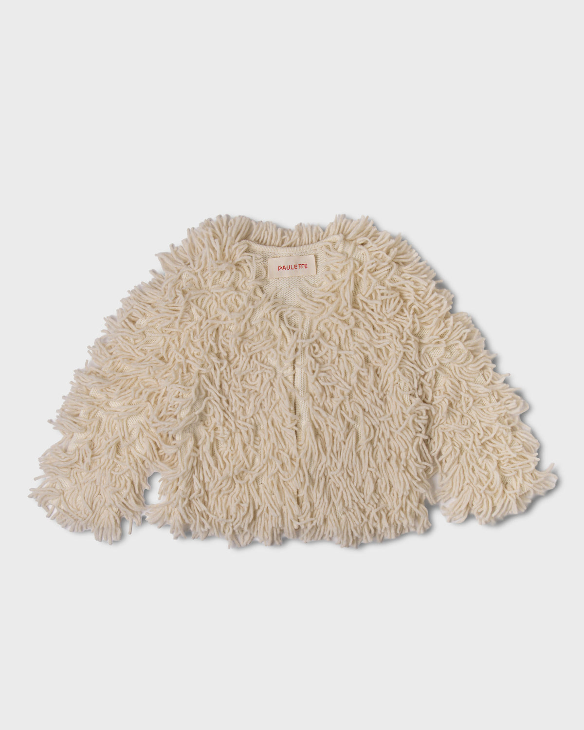 Ivory Paulette Saint-Jean-de-Luz Cardigan displayed against a light gray background, showing a wide, short silhouette, long sleeves, and shaggy strands extending beyond the cuffs and hem.