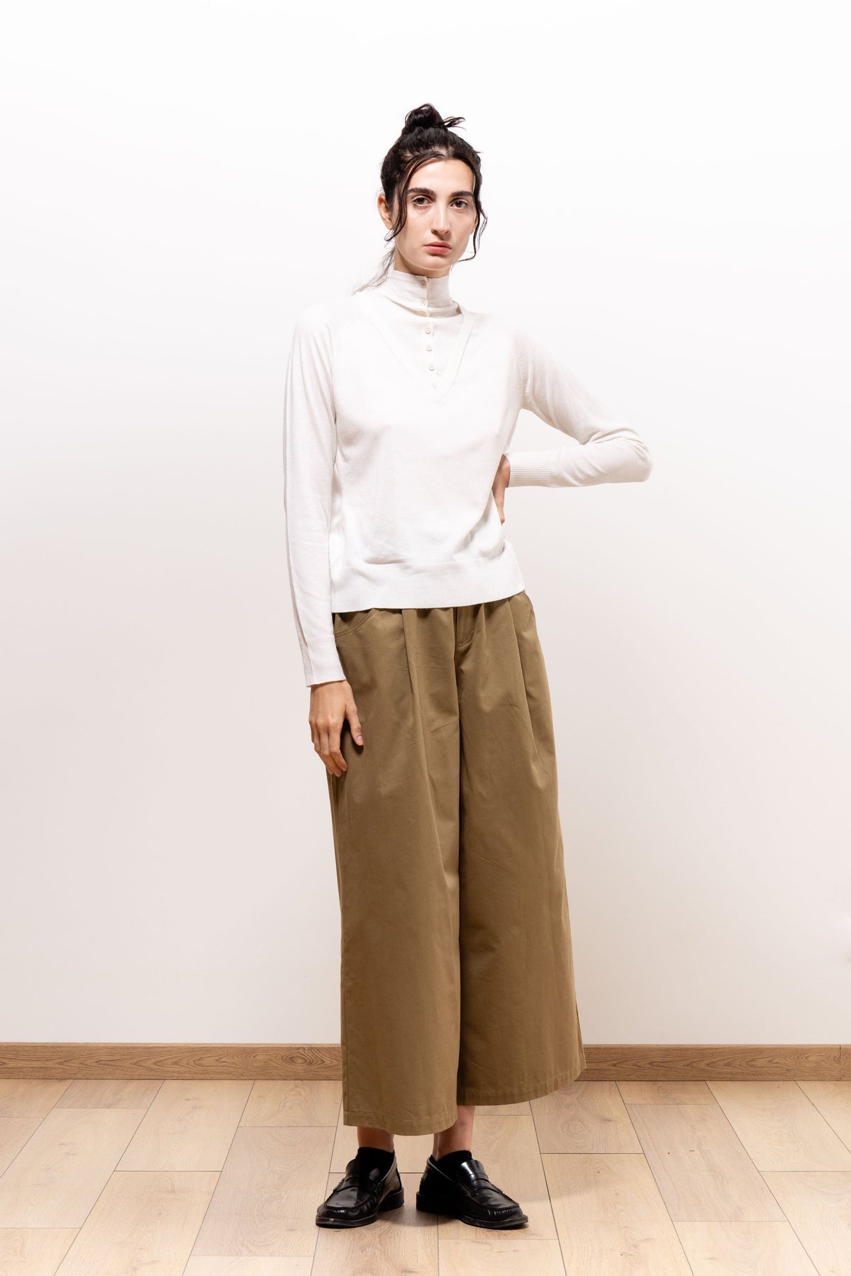 Full-length front view of a model wearing khaki-brown Paulette Lee Trousers with an ivory long-sleeved top and black shoes, showing the loose, wide legs ending above the ankles.