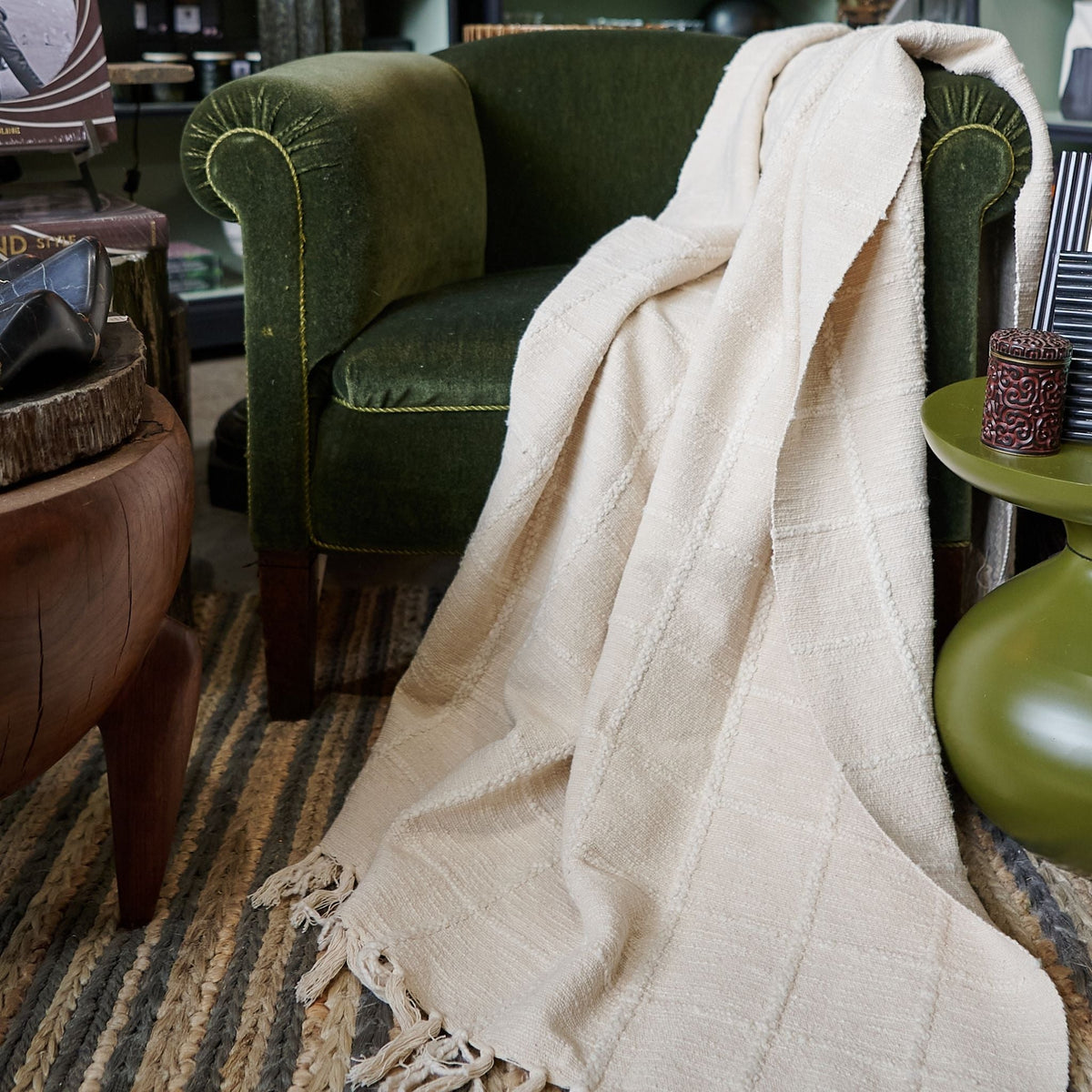 Sea Shell White fringed throw draped over the arm and seat of a deep green velvet chair