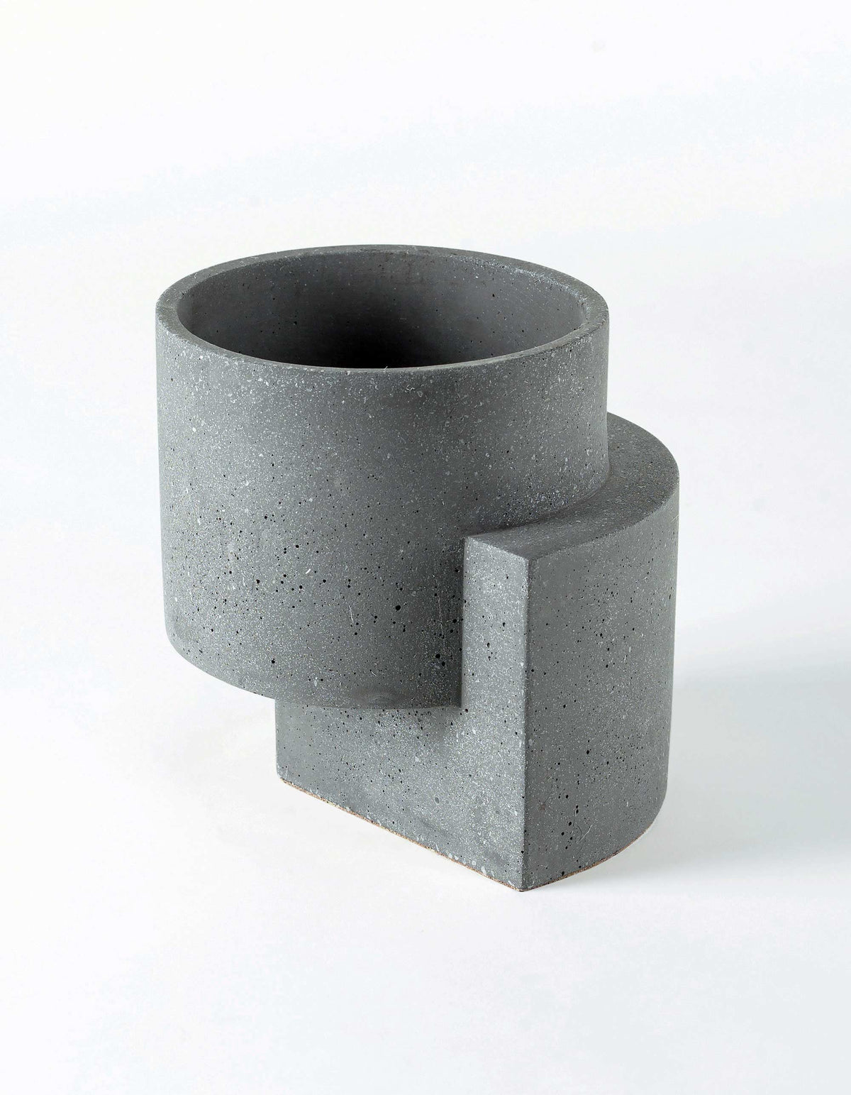 Graphite Tortuga Forma Platform Planter Medium Terrazzo on white, showing its dark circular interior, pale surface flecks and curved vertical support beside and beneath the cylindrical bowl.