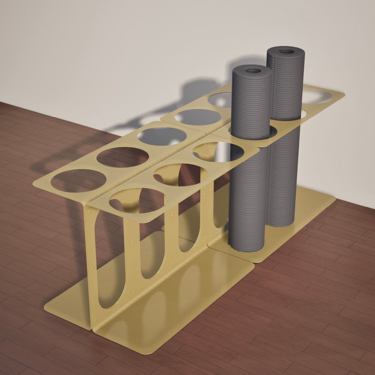 Gold floor stand holding four gray rolled mats or foam rollers, showing the long rectangular base and open storage slots.