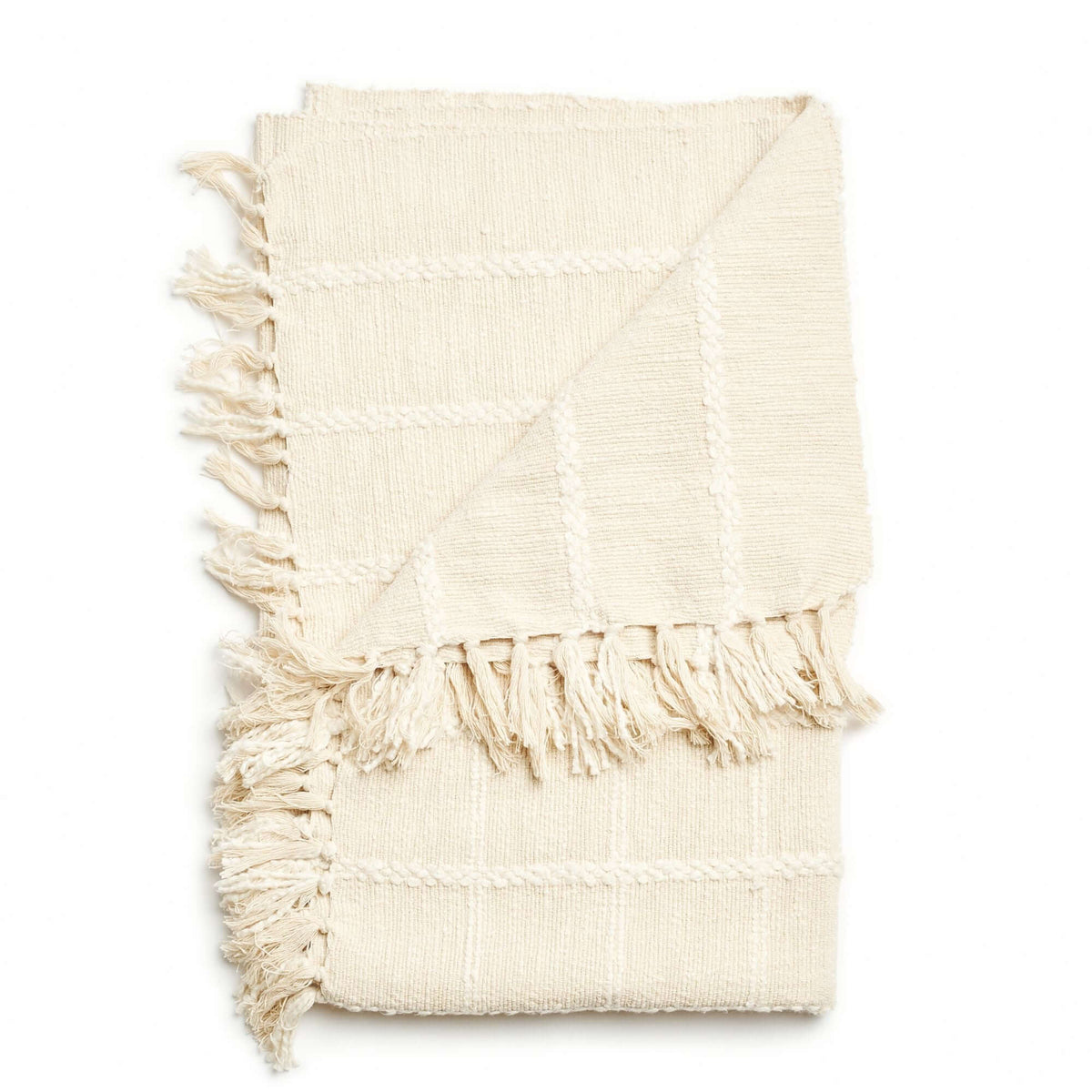 Folded Sea Shell White handloom throw with its raised check pattern and knotted fringe layered across the center