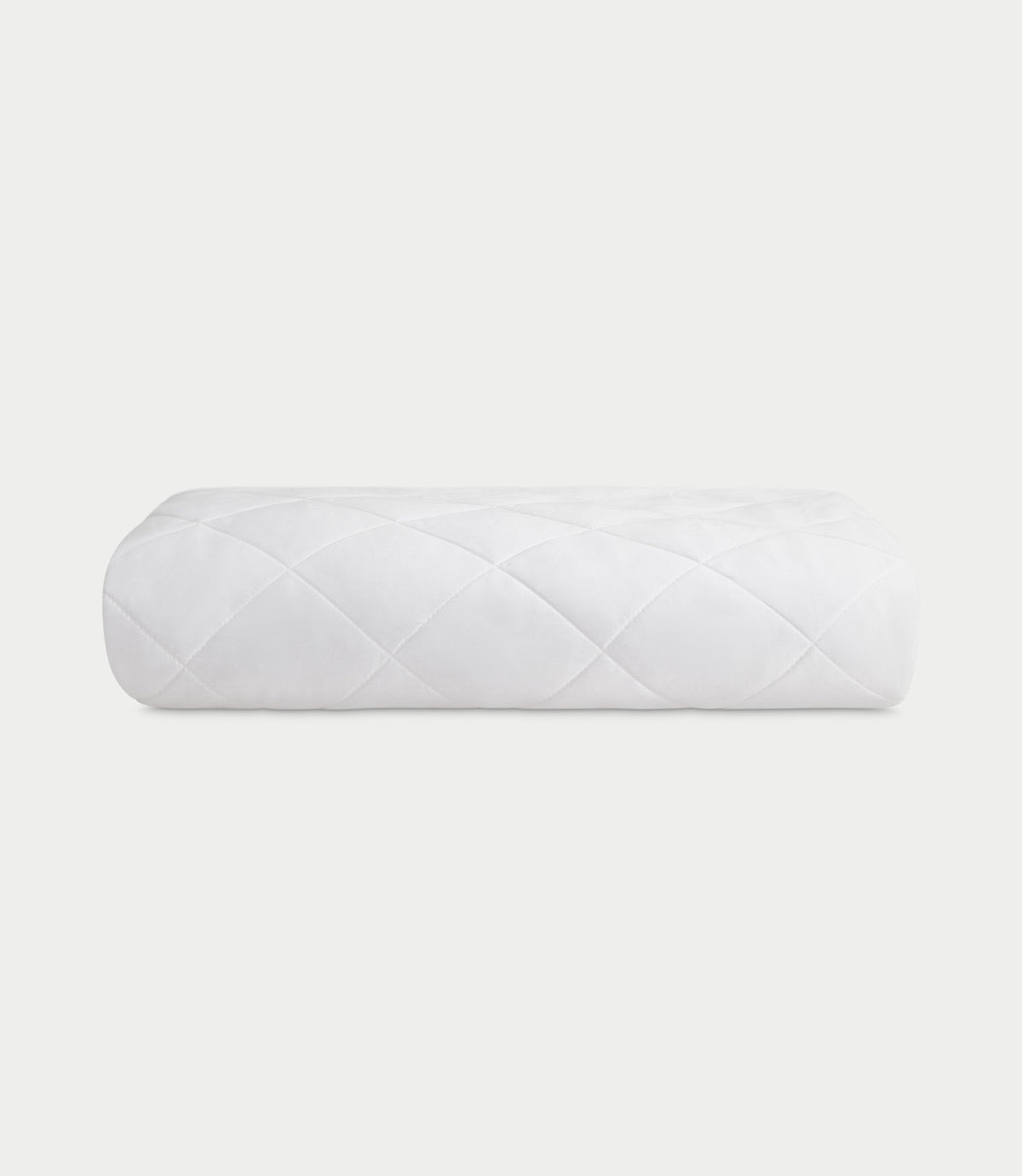 White mattress pad folded into a compact rectangular stack on a pale background, with diamond quilting visible across the front.