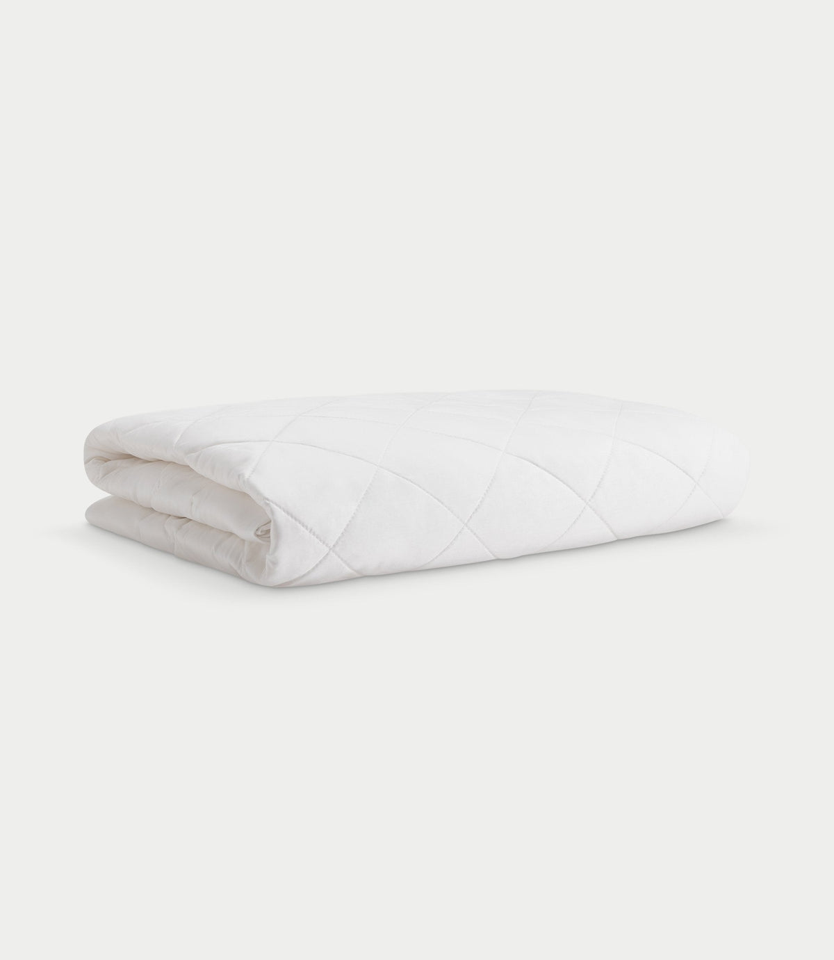 White Bamboo Mattress Pad folded on a pale background, showing its padded diamond quilting, rounded folds, and tucked fabric edges.