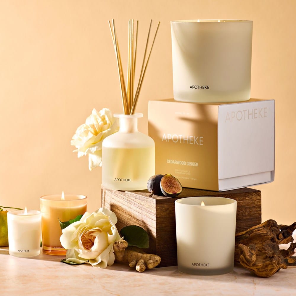 APOTHEKE Cedarwood Ginger 3-Wick Candle displayed with matching reed diffuser and votive candle in a styled vignette