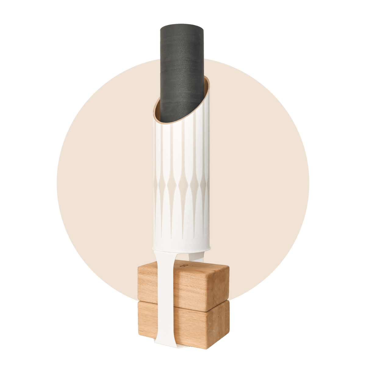 White cylindrical yoga storage tube with a vertical tan elongated-diamond pattern, holding a rolled black mat and standing on four natural wood blocks.