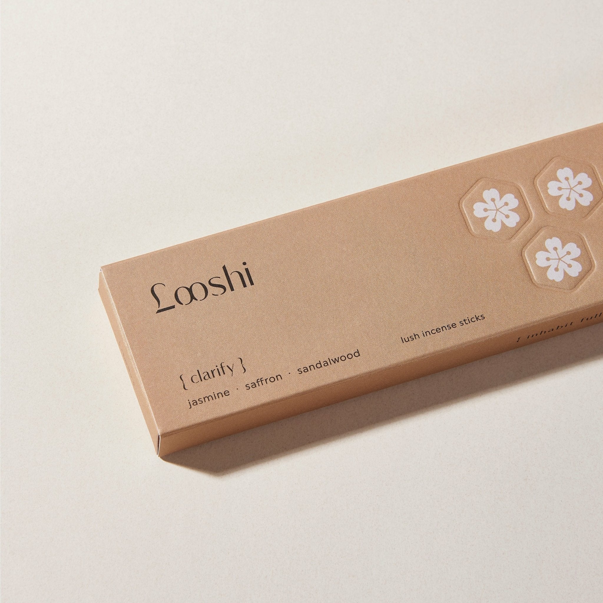 Tan box of Looshi Clarify incense sticks with white floral details, featuring jasmine, saffron and sandalwood fragrances