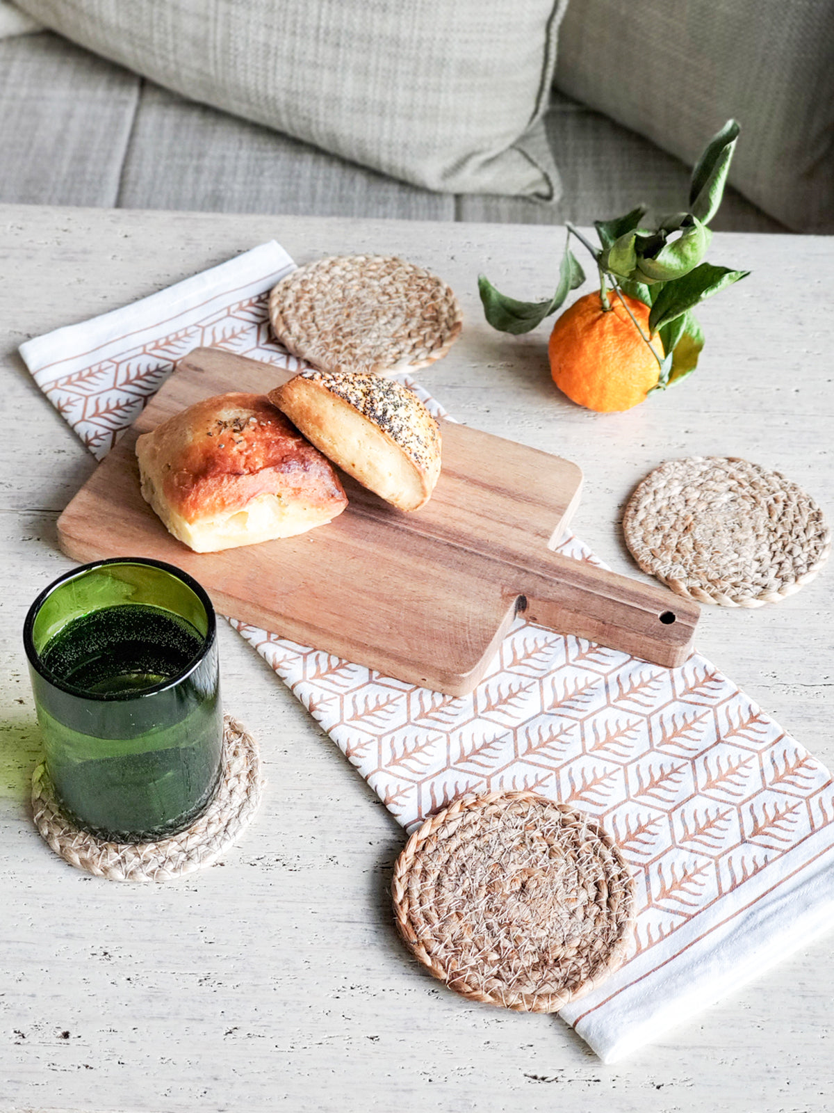 Korissa Kata Natural Drink Coaster styled with bread, tangerine, green glass