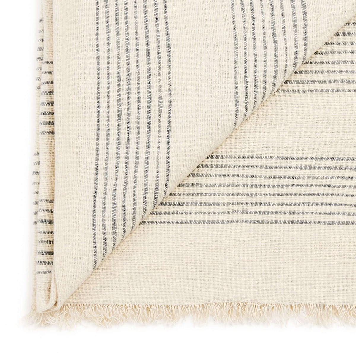 Close-up of the Silica Chalk throw’s folded corner, fine gray stripes and soft cream fringe