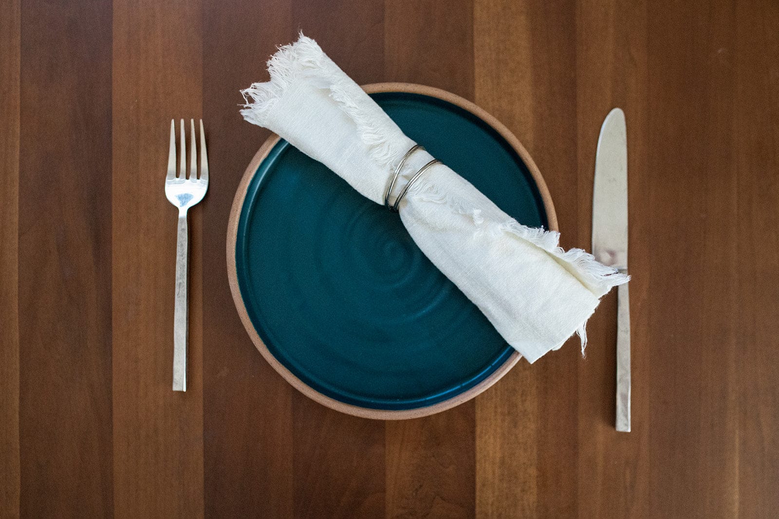 Teal glazed handmade dinner plate with linen napkin and flatwar