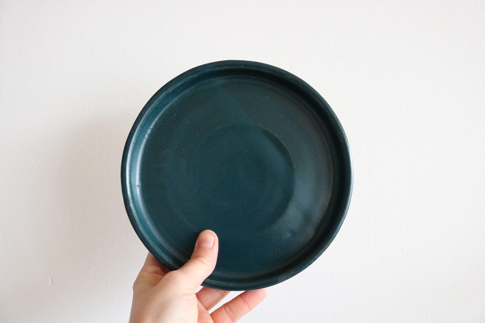 Teal handmade small earthenware plate held in hand