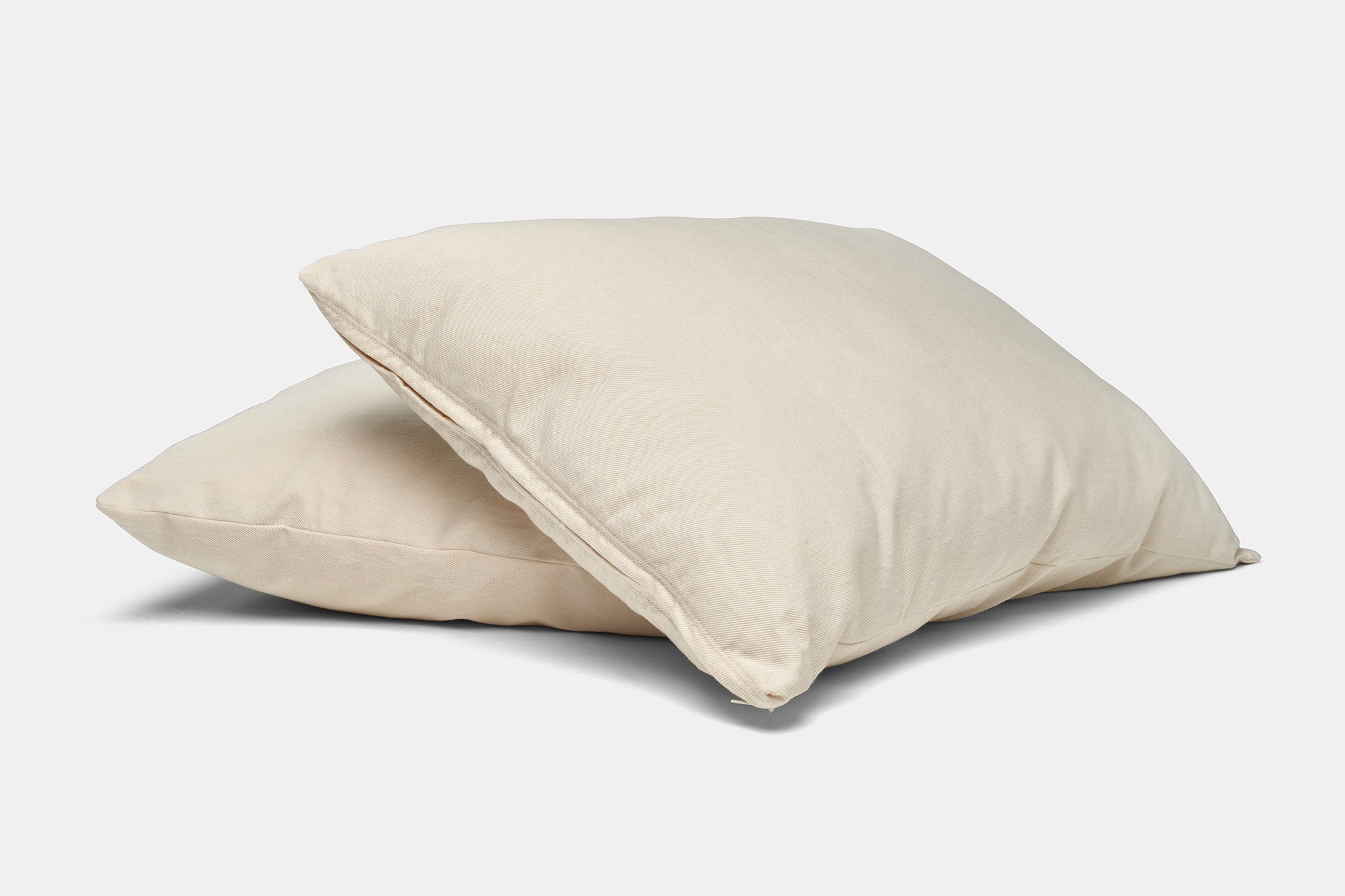 Two beige pillows stacked on a light gray background