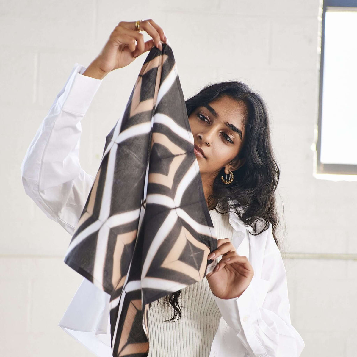 Woman holding up one corner of the lightweight patterned cotton napkin.
