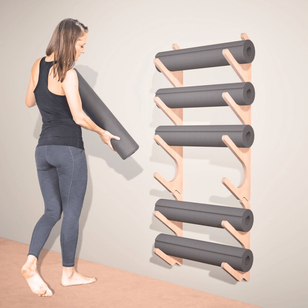 Wall-mounted yoga prop organizer holding rolled yoga mats