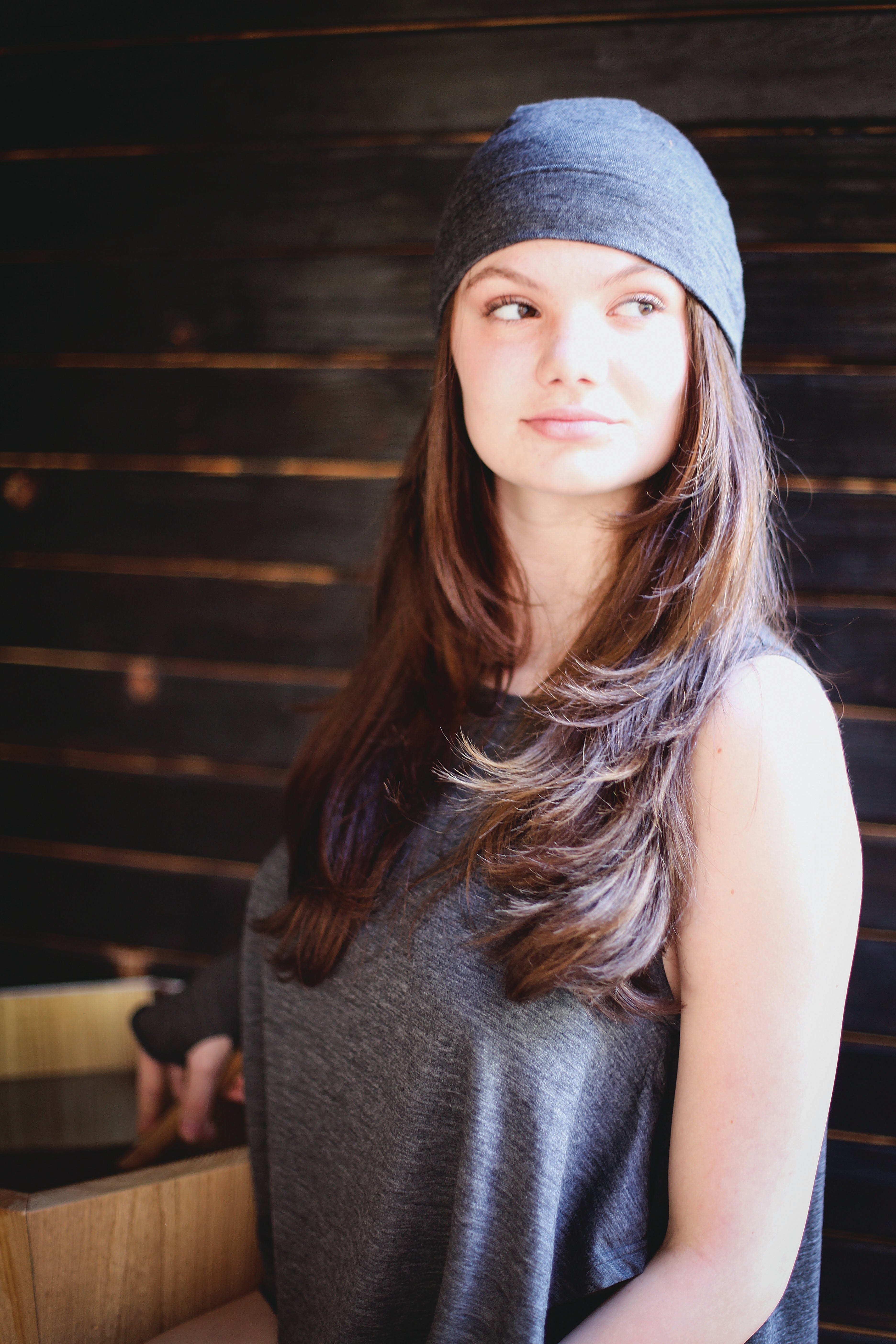 Woman wearing a charcoal merino wool sauna hat for sauna bathing, cold weather, travel, and wellness routines.