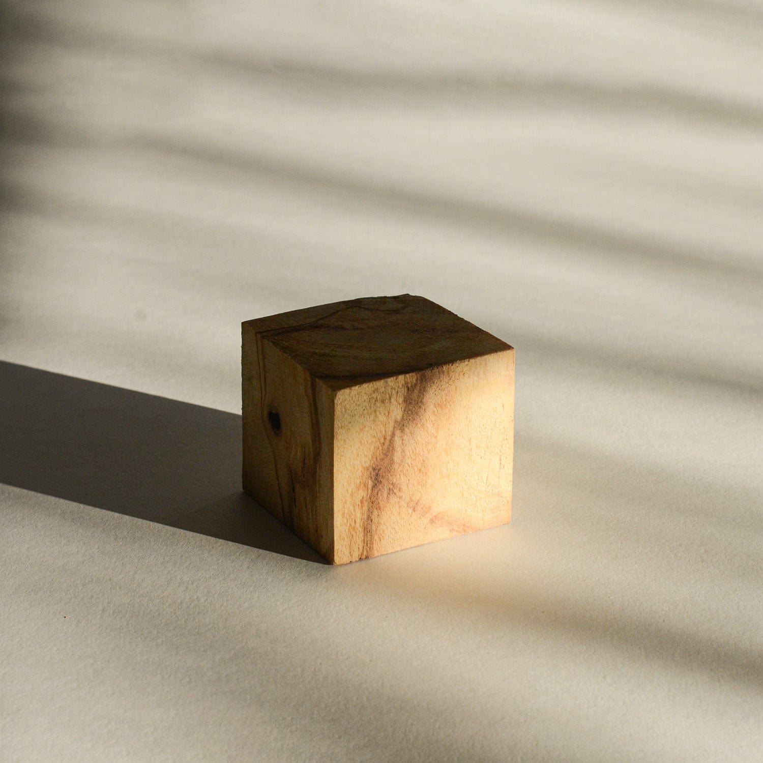 Wooden cube casting a shadow on a textured surface