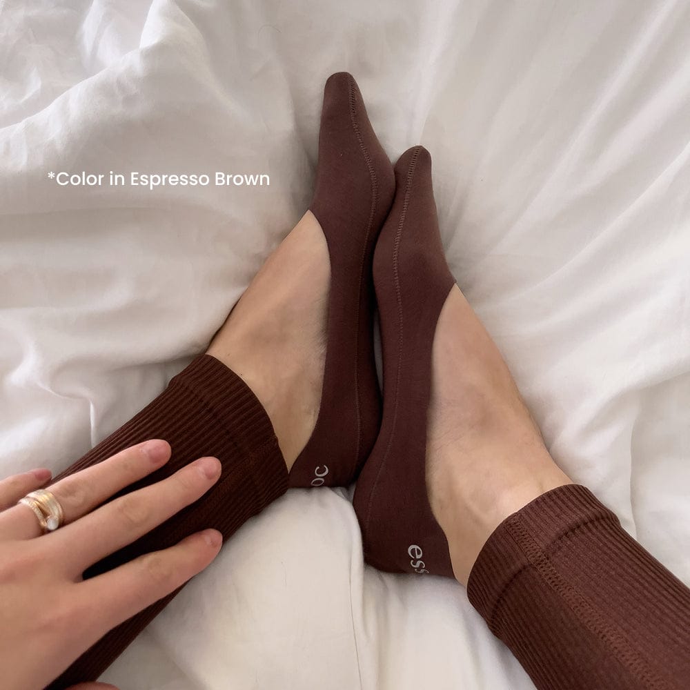 Brown socks being worn on a white bed