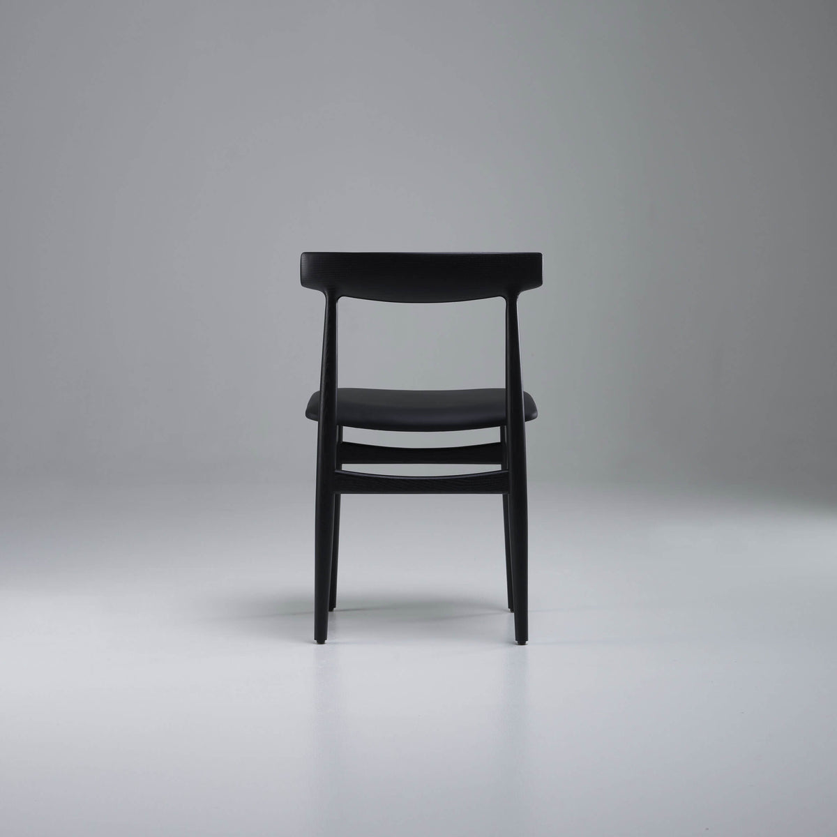 Rear view of the black Eikund Hertug Dining Chair, showing two slim back uprights and curved horizontal rails beneath the seat.