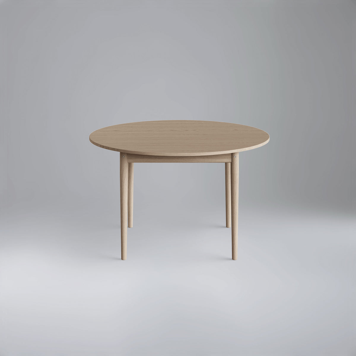 Light wood Eikund Oma Static Dining Table in a gray studio, viewed slightly from above to show its round tabletop, visible grain, and slender legs.