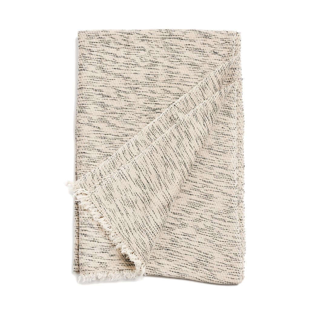 Folded neutral cashmere-merino scarf showing its fine dark flecks and short fringe.