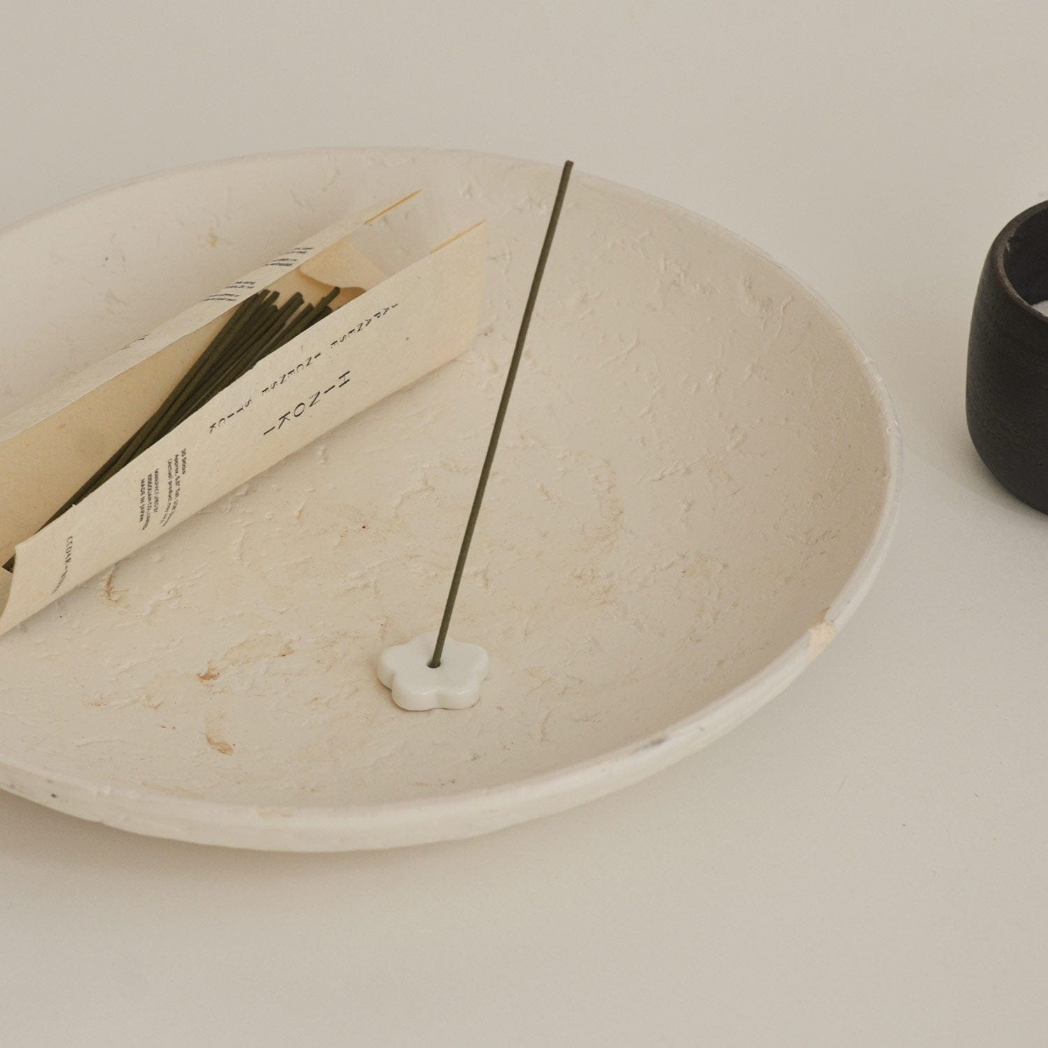 Incense stick on a white plate with a minimal background