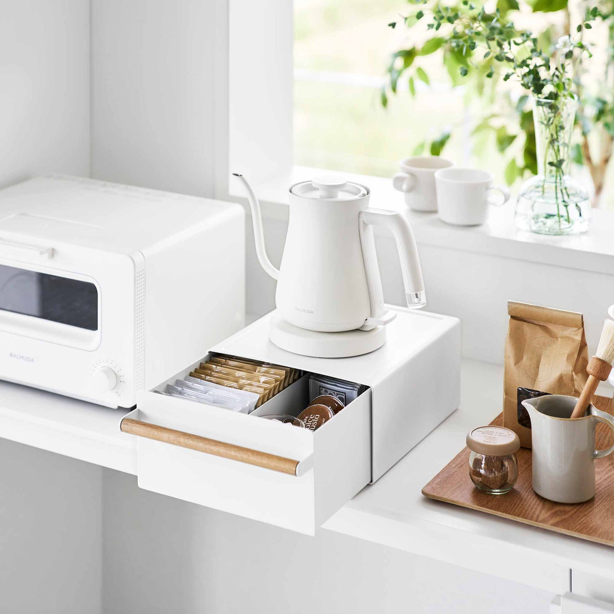 Yamazaki Home Countertop Rack with Drawer - Steel + Wood beneath a white kettle, with the drawer pulled open to show packets and small items beside a countertop oven.