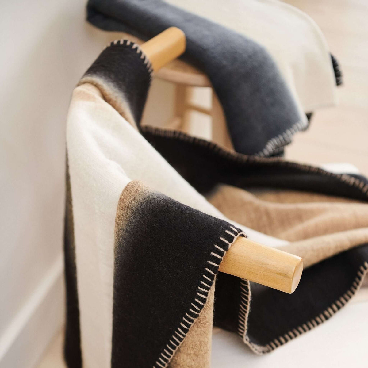 Close angled view of the Siro Brown throw folded over a wood chair arm, showing cream, tan and black panels
