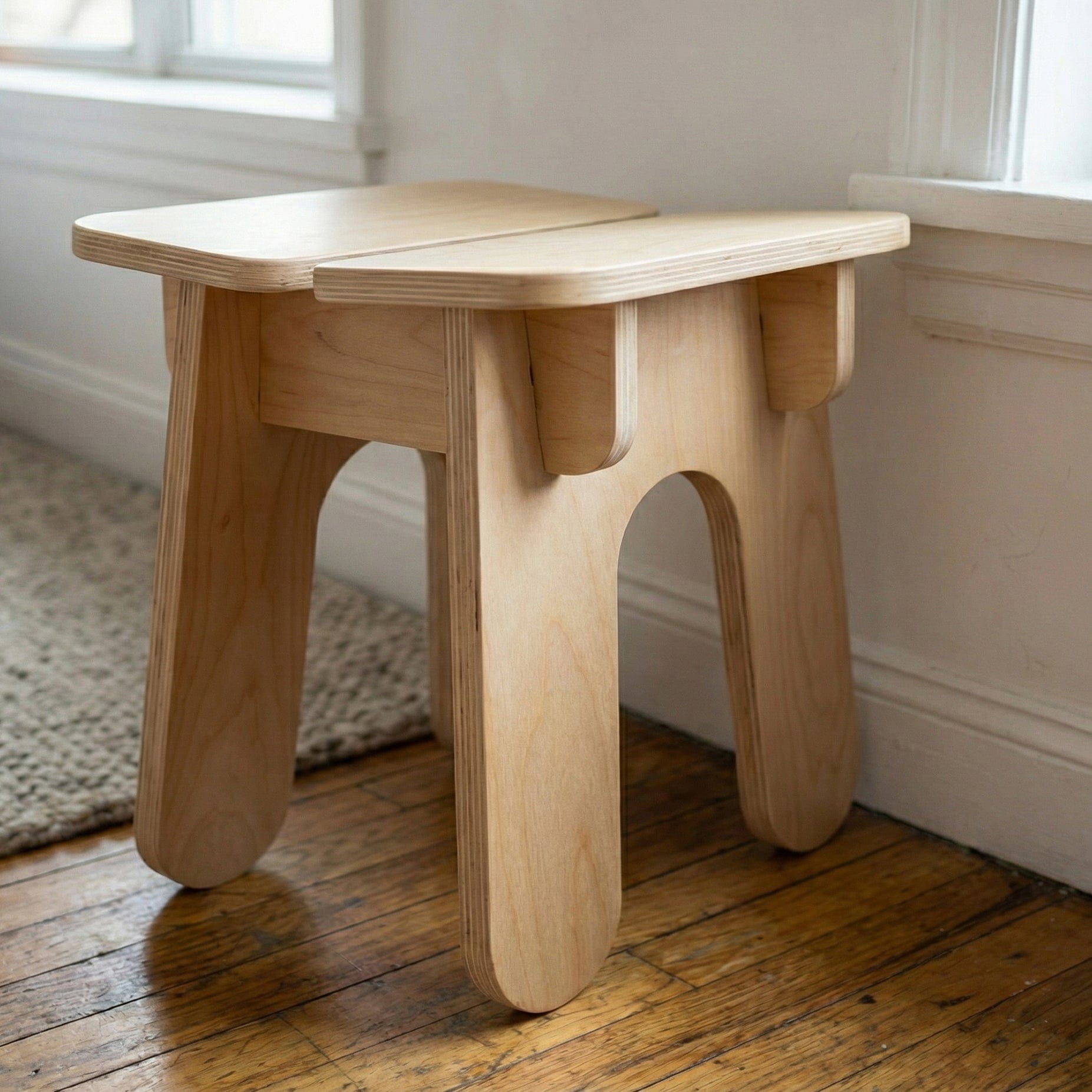 Three-quarter view of the BURIJ wood stool showing its square split-panel seat, projecting corners and sculptural legs