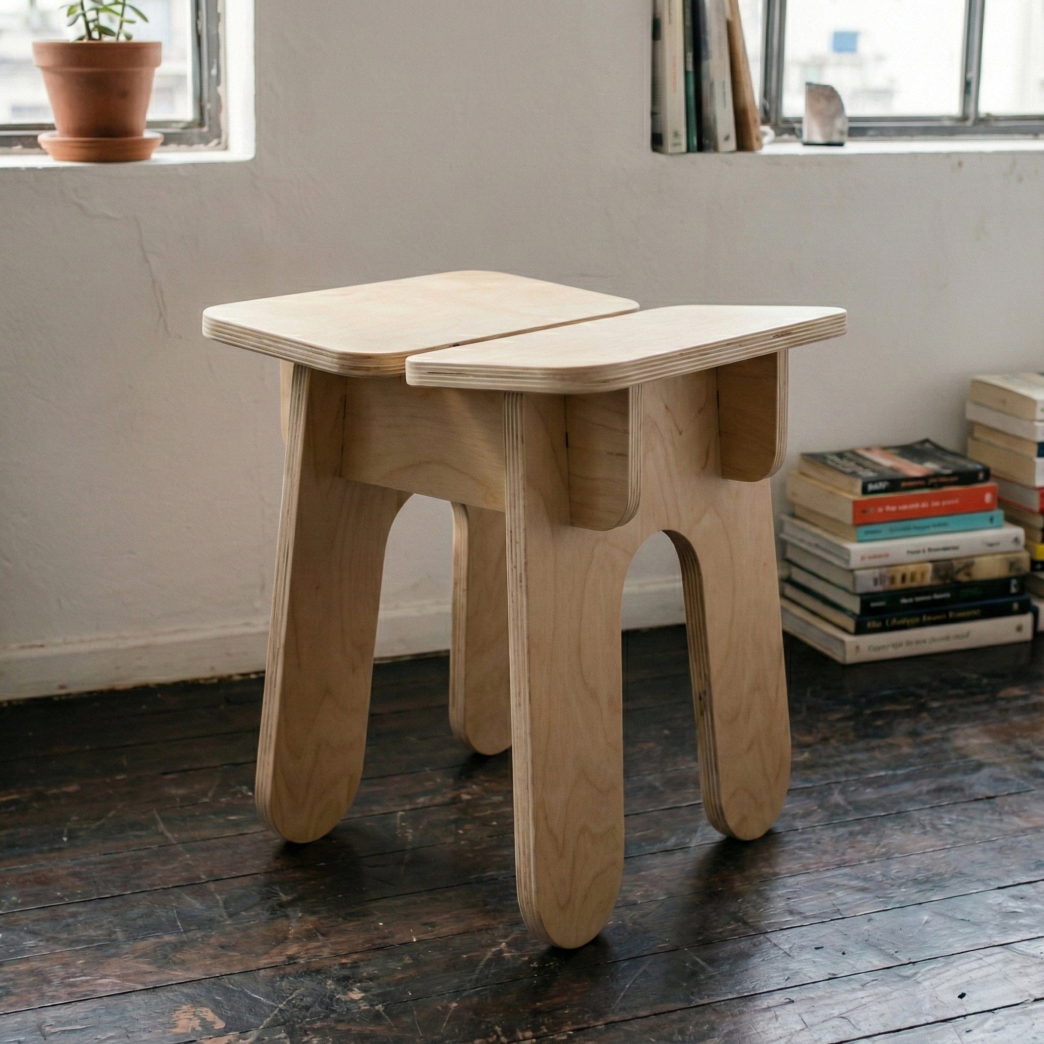 Angled view of the BURIJ stool showing its pale square seat, layered wood construction and four broad rounded legs