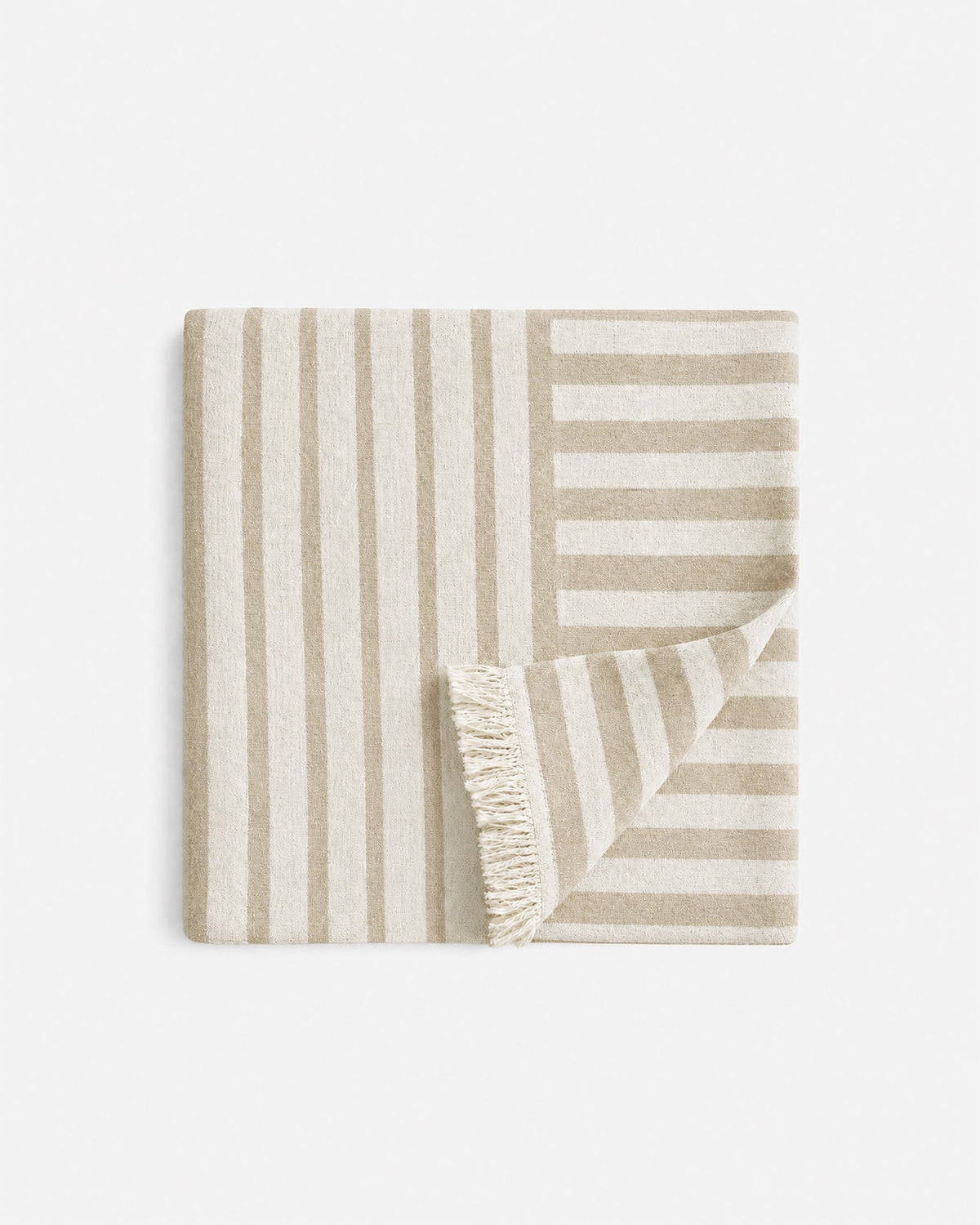 Folded beige and cream Serena Beach Blanket with contrasting vertical and horizontal stripes, with one corner turned back to reveal cream fringe.