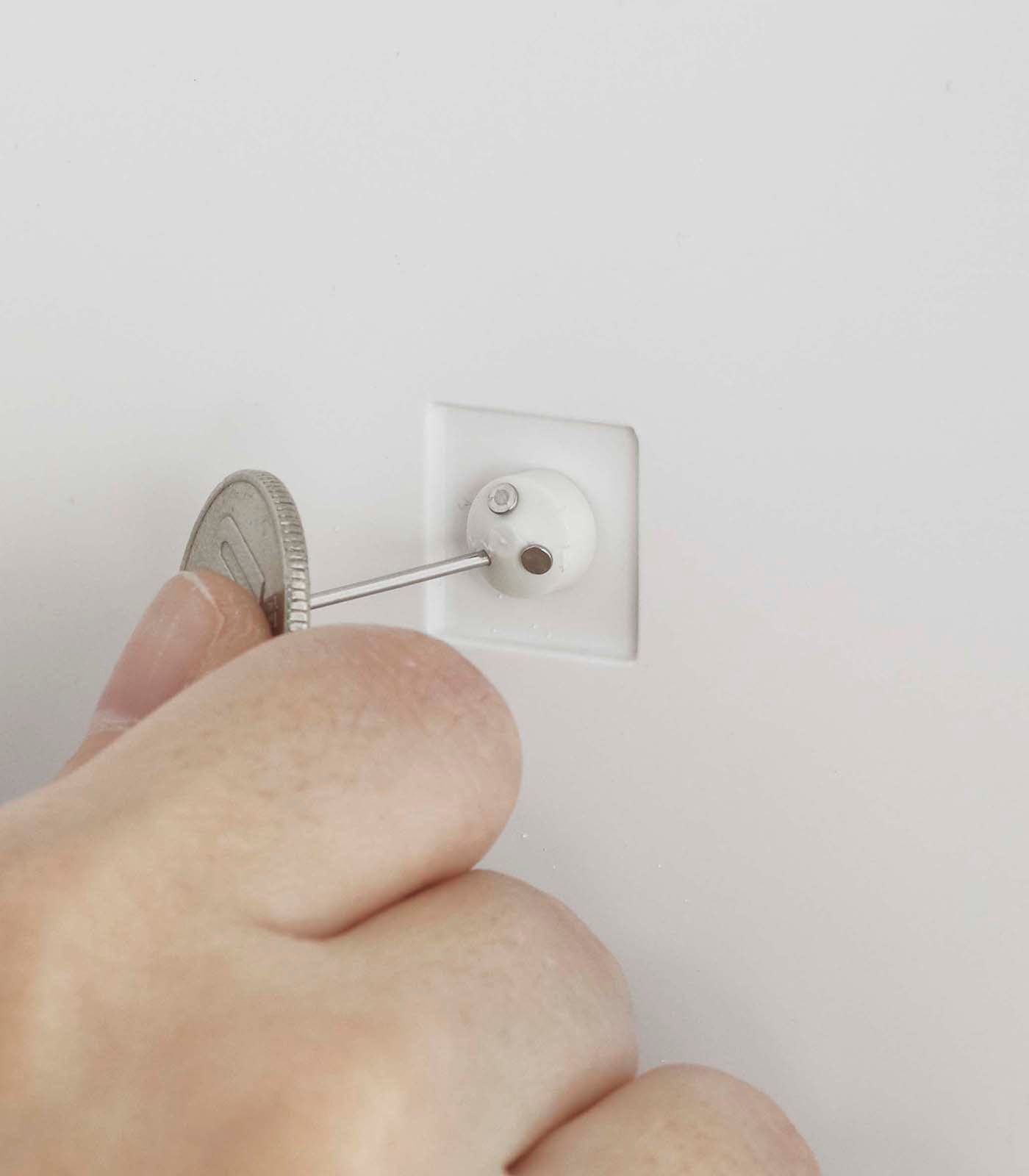 Hand using a screwdriver to remove a wall outlet cover plate.
