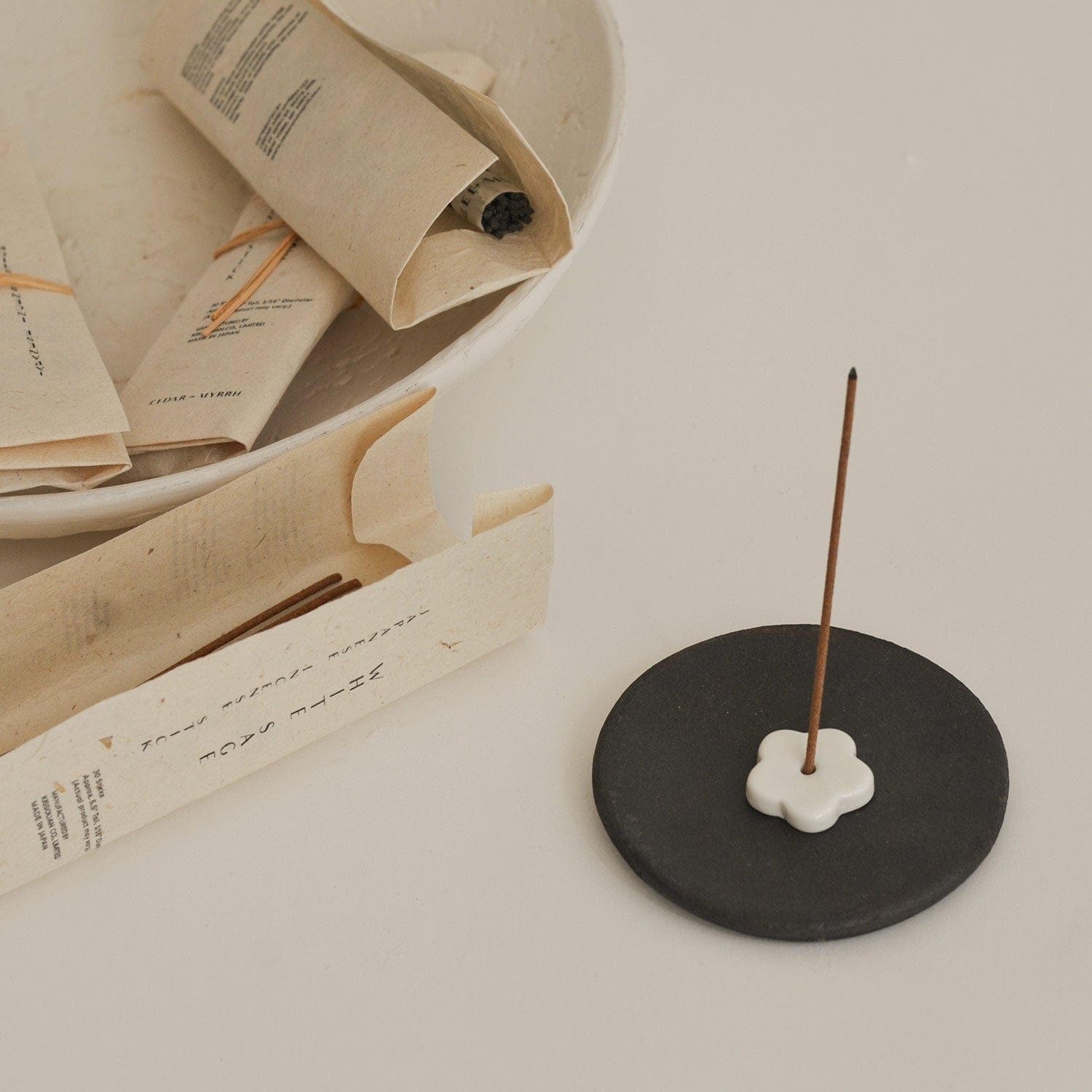 Incense stick on a black ceramic holder with books in the background