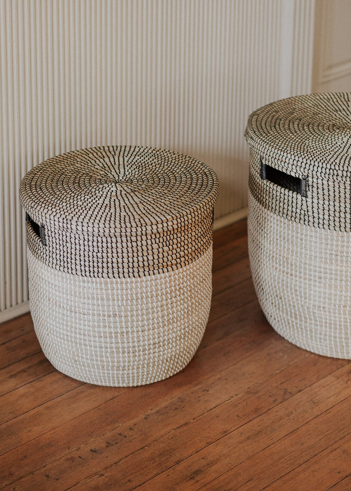 Close lifestyle view of two Black Medina basket sizes on a warm wood floor.