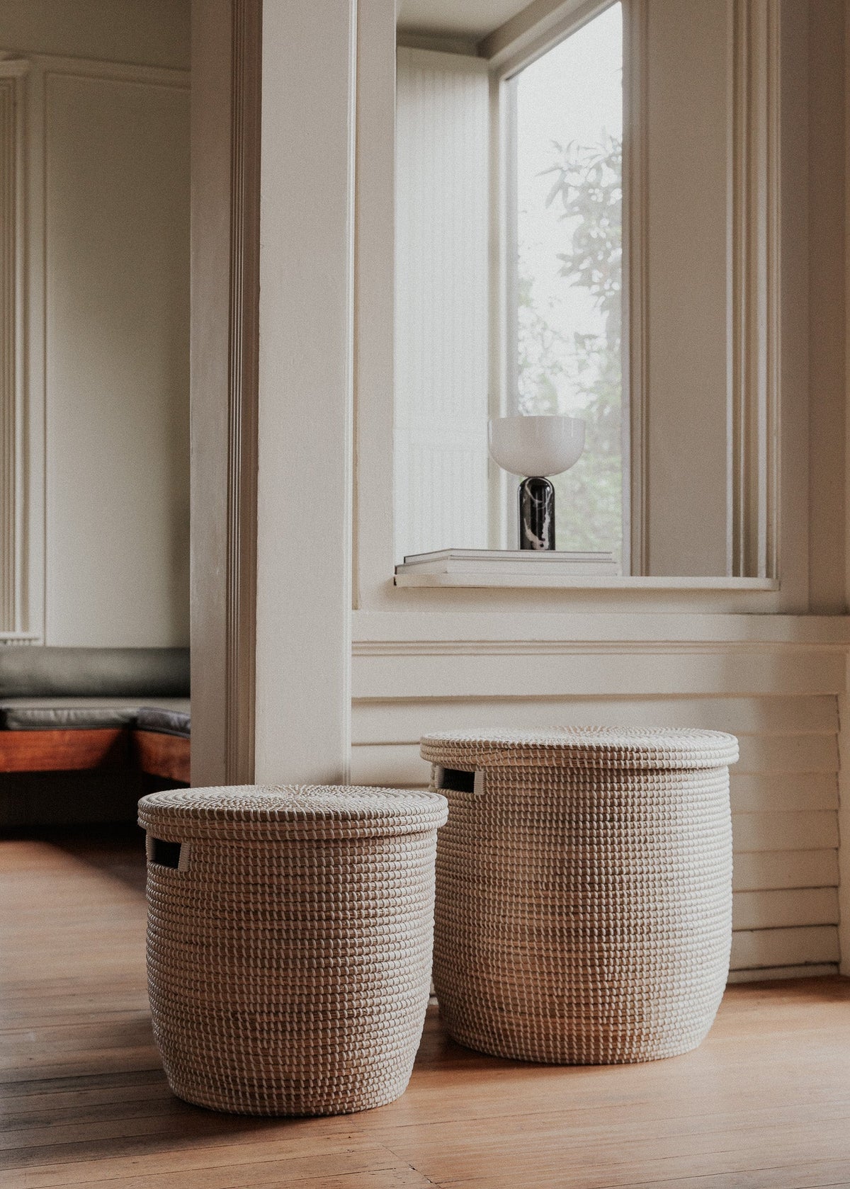 Two sizes of the Medina basket arranged beside tall windows in a softly lit room.
