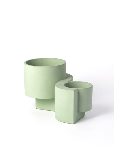 Pale green Tortuga Forma Platform Planter Set on white, with a larger planter behind a smaller one, showing open round bowls, smooth surfaces and curved slab supports.