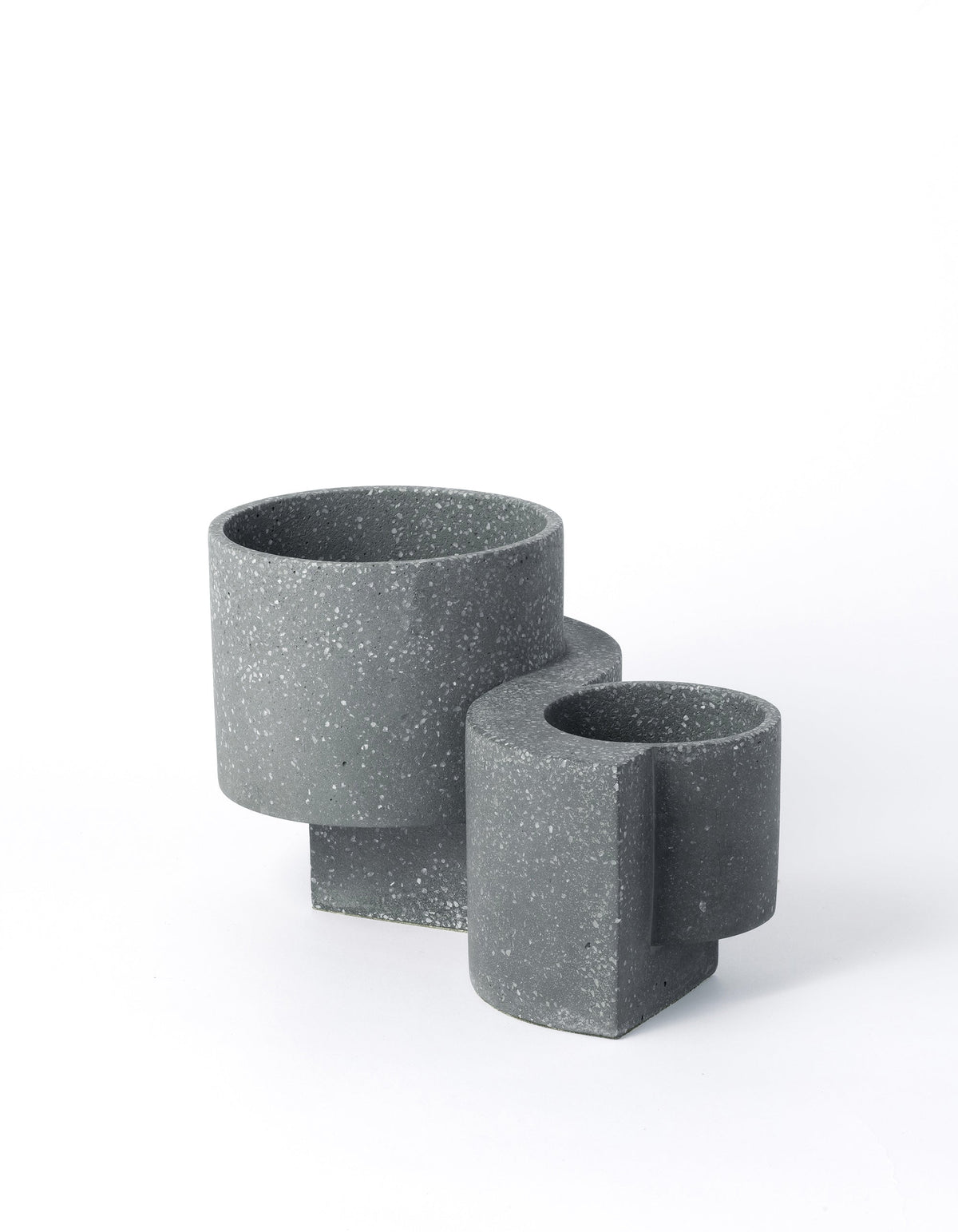 Graphite Tortuga Forma Platform Planter Set on white, with a larger pot behind a smaller one, showing pale terrazzo flecks, open cylindrical bowls and offset slab supports extending beneath them.