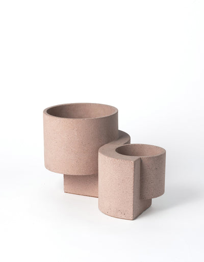 Coral Tortuga Forma Platform Planter Set on white, with the larger planter behind the smaller one, showing pink speckled surfaces, cylindrical bowls and stepped geometric bases.
