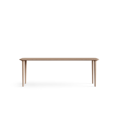 Low long-side view of the light wood Eikund Evja Rectangle Coffee Table, showing its thin tabletop profile, softly rounded ends, and tapered legs positioned near the corners.