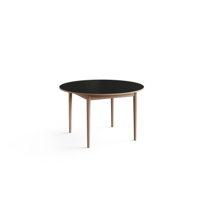 Three-quarter view of the Eikund Oma Static Dining Table with a black circular top and light wood base, showing the thin tabletop profile and angled supports beneath.