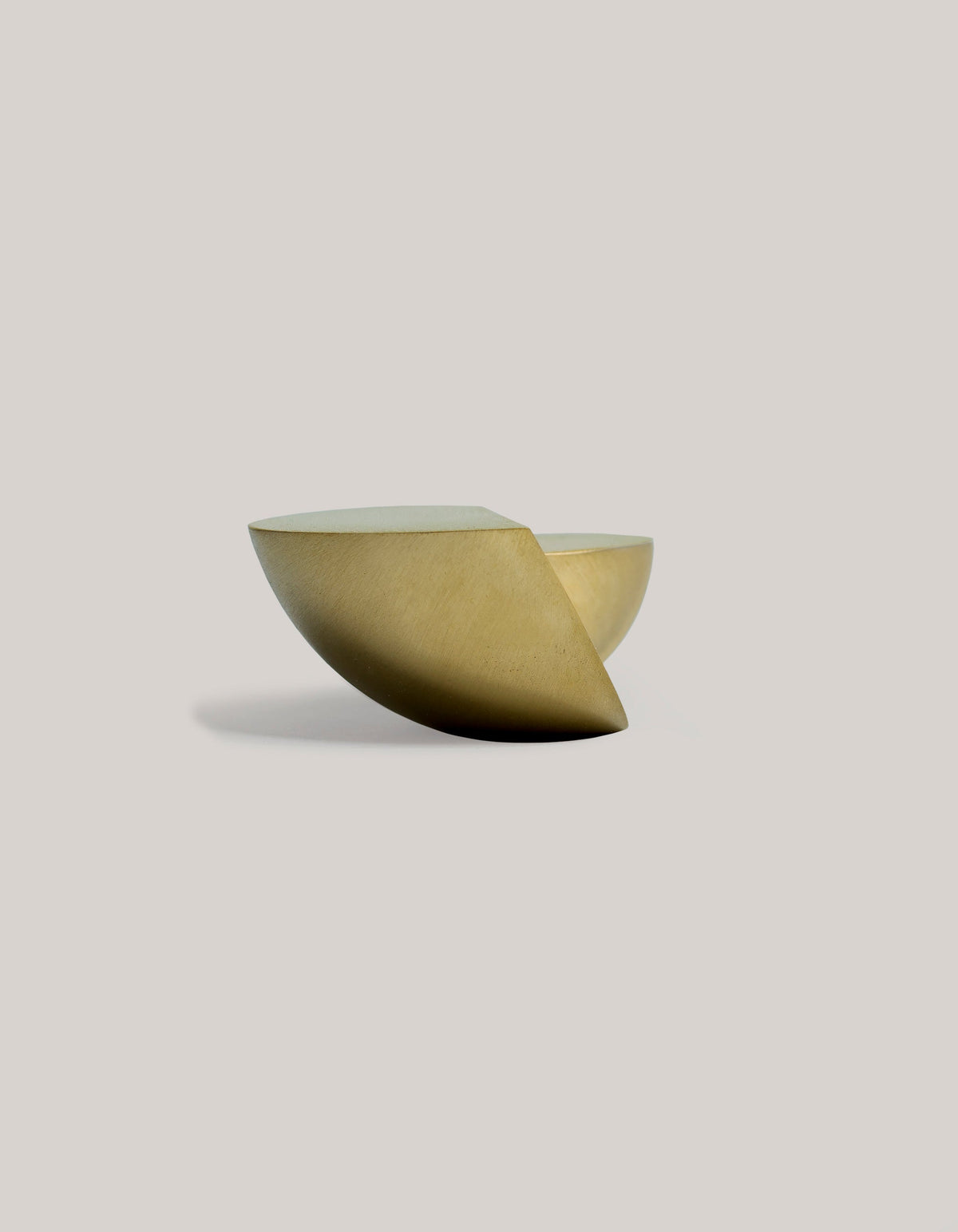 Side view of Tortuga Forma Kaolin Brass Utensil Holder on a light grey background, showing its rounded brass body, curved underside and overlapping raised sections.