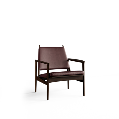 Three-quarter front view of the Eikund Broadway Lounge Chair with reddish-brown leather upholstery and a dark wood frame, showing a sloping backrest, slim seat cushion, angular armrests, and four slender legs.