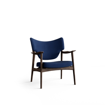 Three-quarter front view of the Eikund Veng Lounge Chair with deep blue upholstery and a dark brown wood frame, showing a broad wing-shaped backrest, separate padded seat, sculpted armrests, and slender tapered legs.