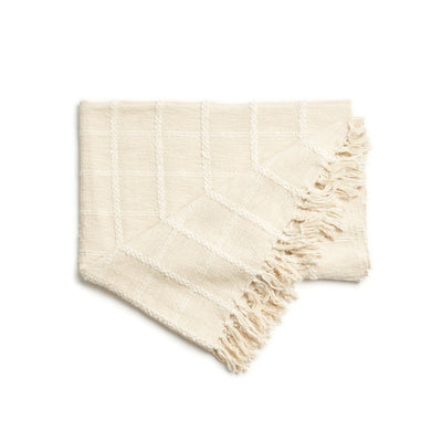 Folded Sea Shell White handloom throw angled against a white background with one fringed corner spread outward