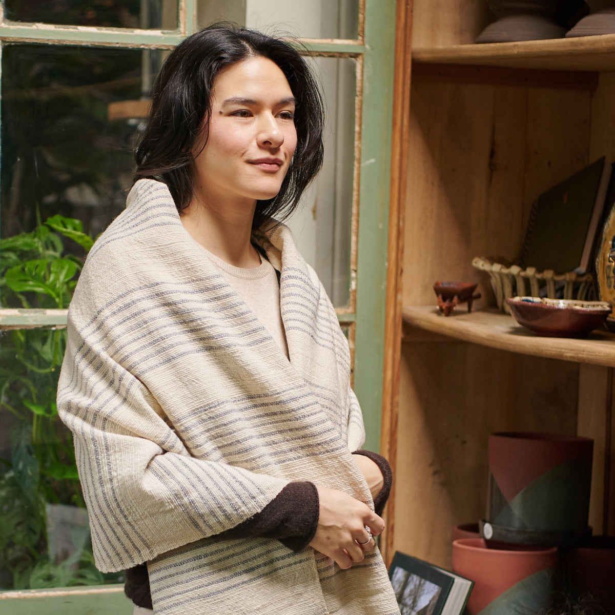 Woman wearing the Silica Chalk handwoven throw around her shoulders, displaying its soft drape and varied gray stripes